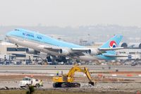 HL7472 @ LAX - Korean Air HL7472 (FLT KAL18) departing RWY 25R enroute to Incheon Int'l (RKSI) as work crews continue work on RWY 25L in the foreground.