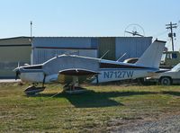 N7127W @ FWN - An elderly 1962 Piper Cherokee 180 tries not to have anything to do with the automotive debris in the background. - by Daniel L. Berek