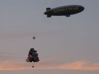N3A @ KOSH - Goodyear Blimp and N878UP Cluster Ballon Lifting off into setting sun Oshkosh 2010 airshow - by steveowen