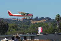 N757NQ @ KCCR - Pacific States Aviation 1977 Cessna 152 over the fence at Buchanan Field (say, Who's that lady on the billboard?) - by Steve Nation