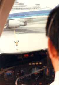 JA8530 @ RJTT - Japan Air Lines.View from  the cockpit. Marshaller at work. Arrival from Kagoshima , Haneda airport.ANA B747 is leaving. - by Henk Geerlings