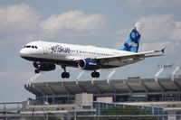 N644JB @ TPA - Jet Blue A320 doing a rare landing on Runway 28 due to high cross winds.  Raymond James Stadium in the background (Tampa Bay Buccaneers NFL football) - by Florida Metal