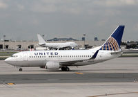N24633 @ KEWR - A United Boeing 737-524 (built 1995) taxies past Newark's terminal C, while a 747 in the background maintains an air of indifference. - by Daniel L. Berek