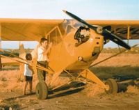 UNKNOWN @ SQL - I am giving this J3C-65 a thorough inspection with my sister looking on. This was at San Carlos airport around 1960-61 when most planes were parked on dirt like this Cub is.