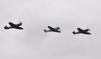 G-IBSY @ EGFH - Three Ultimate Warbirds with Spitfire G-IBSY (Coded DV-V) over Runway 04 leading Buchon G-AWHM (coded Yellow 7) and Spitfire G-SPIT (coded JE-J). - by Roger Winser