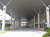  - The BTR terminal drop-off/pickup area. The ternimal is to the right the parkinlot is to the left. Right in front al the way in the back is the rental cars offices area. This arc roof helps to keep away the beating sun in the summer. - by Michael W. Rosa