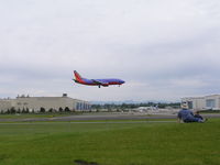  - Southwest 737 landing 16R, Boeing wide body plant background left, paint hangars background right - by John J. Boling