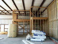  - New hangar under construction. Insulated, internal wall studs, framing for two-story rooms in corner. Photo taKen through picture window opening which overlooks runway. - by Doug Robertson