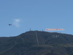  - N65124 Boeing Stearman towing FOLLOW THE BACON-Carl's Jr. advertising banner past South Mountain, viewable by all of Santa Paula, CA. - by Doug Robertson
