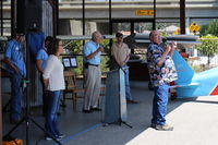  - Bruce Dickenson announcing purchase/dedication of Hangar ONE (behind him) for the Aviation Museum of Santa Paula. His pilot father in 1930 one of the 16 airport founders. Cake was served. - by Doug Robertson