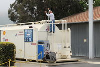  - Pete on the Santa Paula SHELL 100LL Fuel Tank. He drains the sump daily for any condensation H2O. - by Doug Robertson
