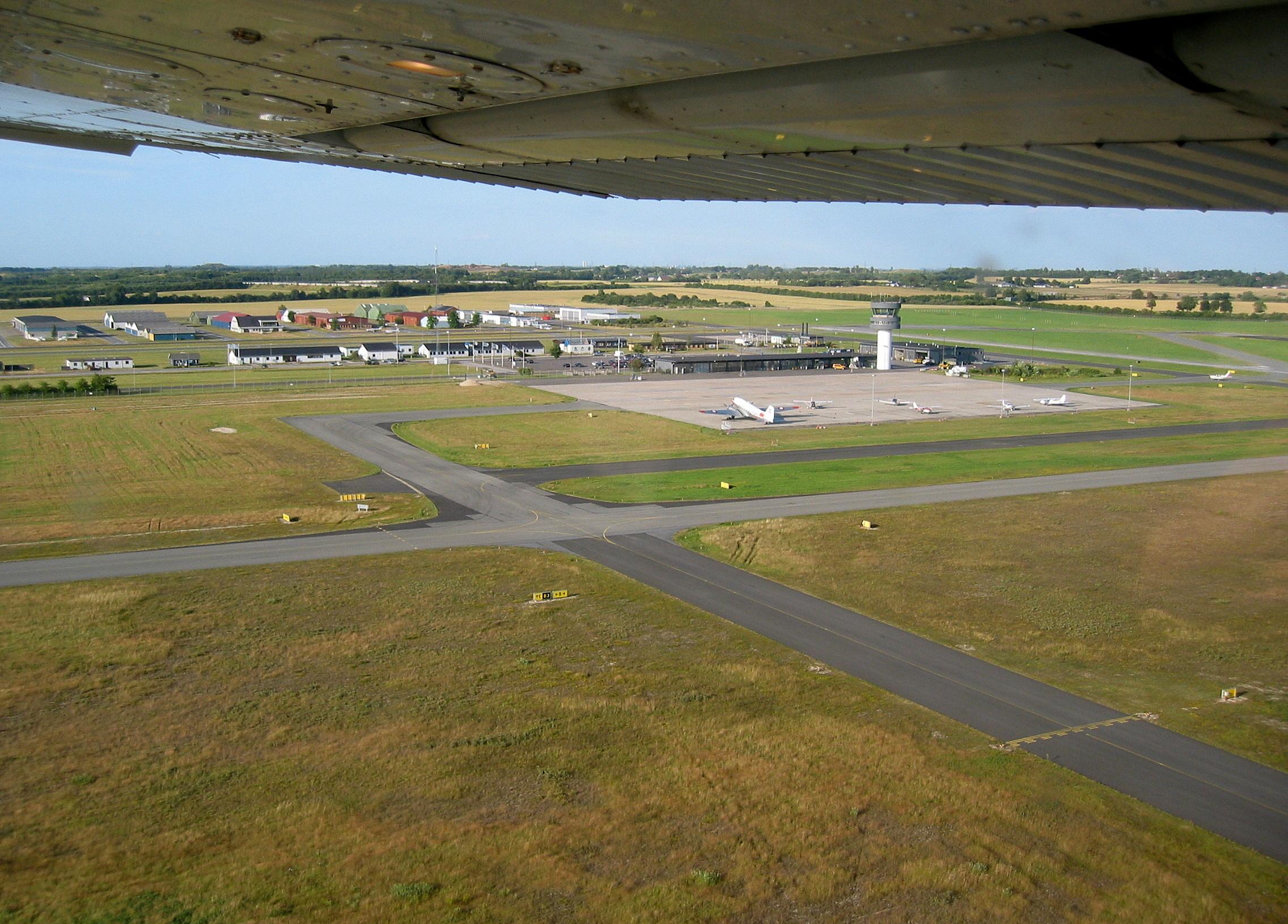  - Roskilde Airport in Denmark seen from Cessna 172 OY-JDL shortly after takeoff from Runway 29 on a flight to the Danish island of Samso. Former Danish Air Force C-47 OY-BPB seen on apron. - by Jan Lundsteen-Jensen